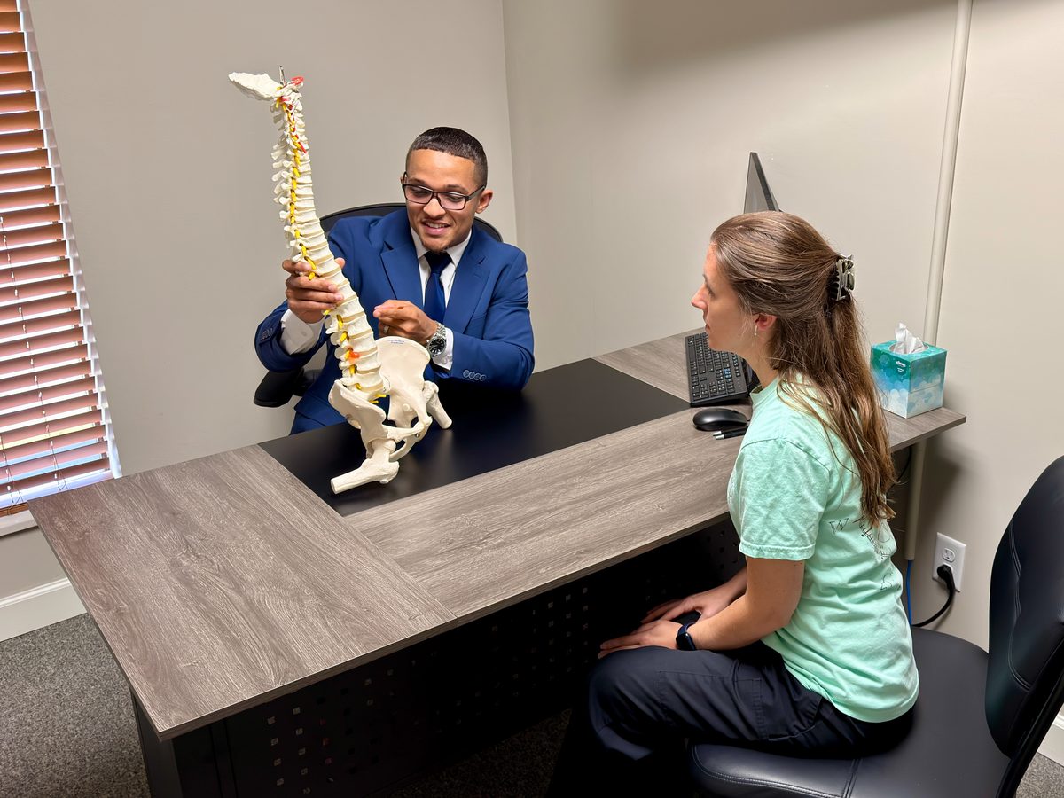 Chiropractor explaining a spine model to a patient during a consultation at Victory Spinal Care
